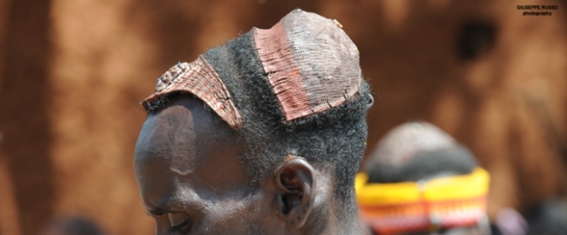 Uomo di etnia Tsemay con sulla testa una crocchia di argilla sormontata da penne di struzzo, detta”cercine”