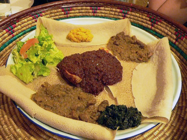Zighinì completo di Injera e spezzatini misti (sul tipico portavivande piatto e circolare fatto di fibre vegetali)