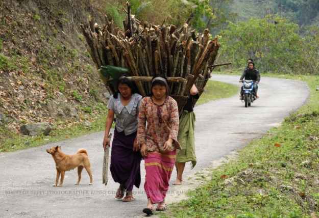 Donne di etnia Nyishi che trasportano sulle spalle le tipiche gerle con le fascine di legna